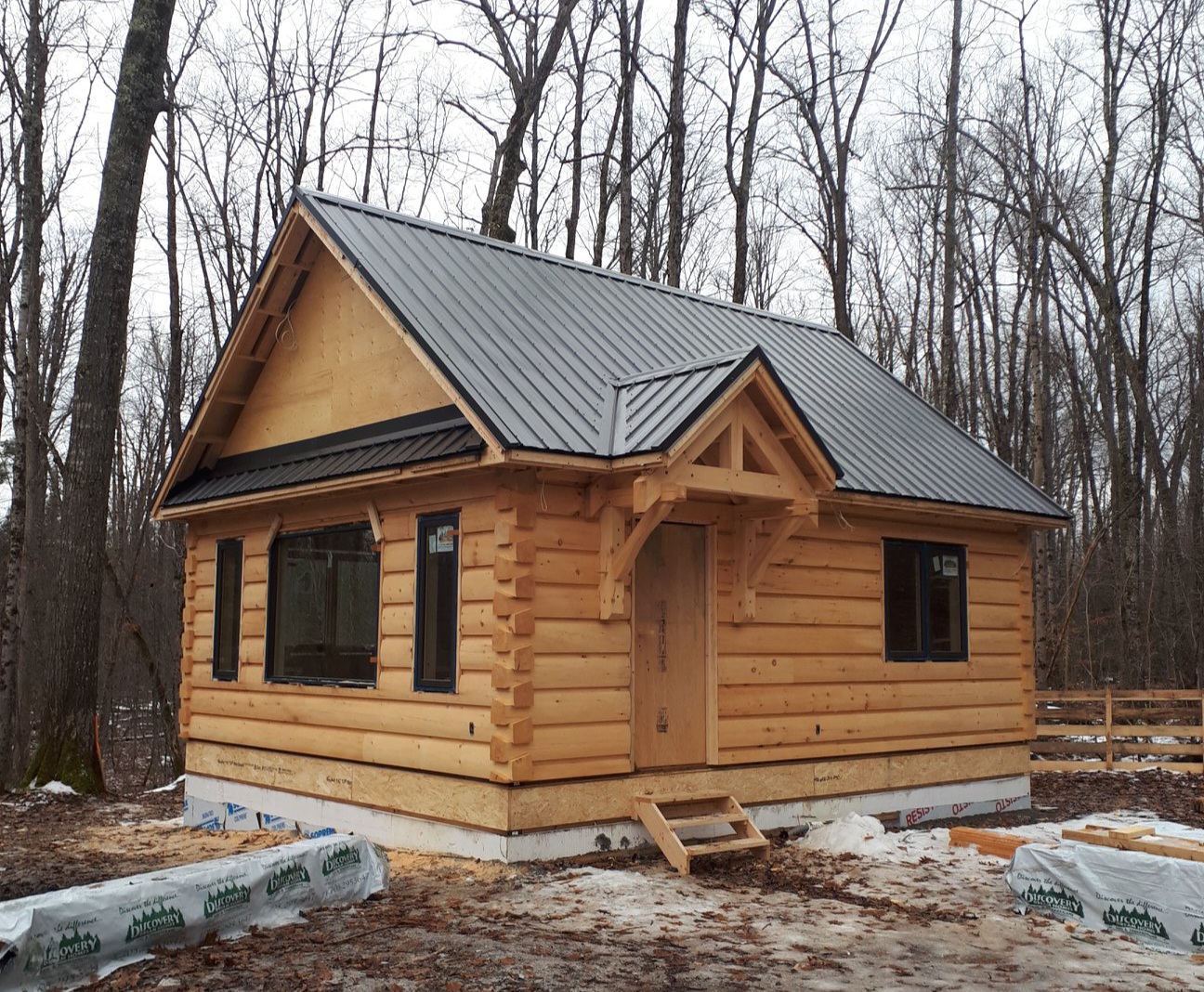 Small log cabin with a finished black metal roof.