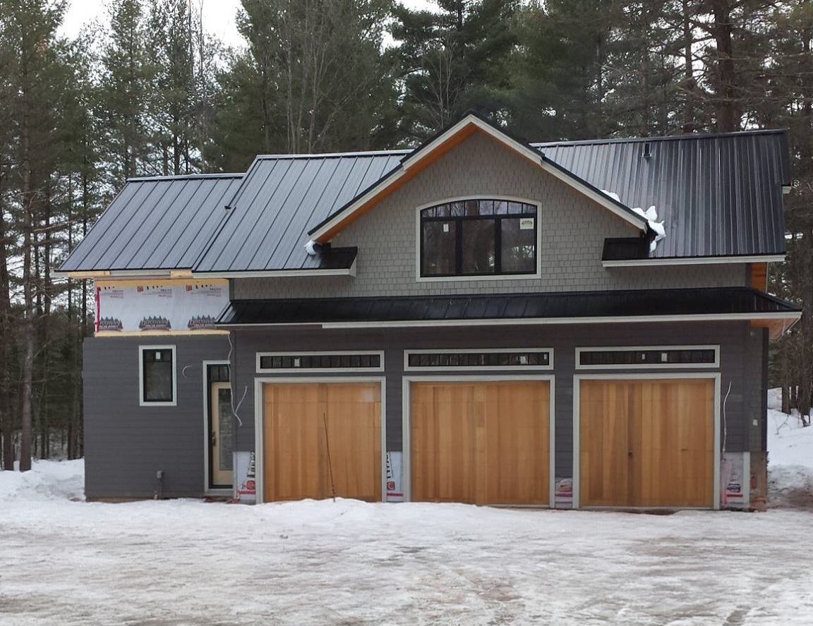 Front view of a garage-home build with a darker steel roof.