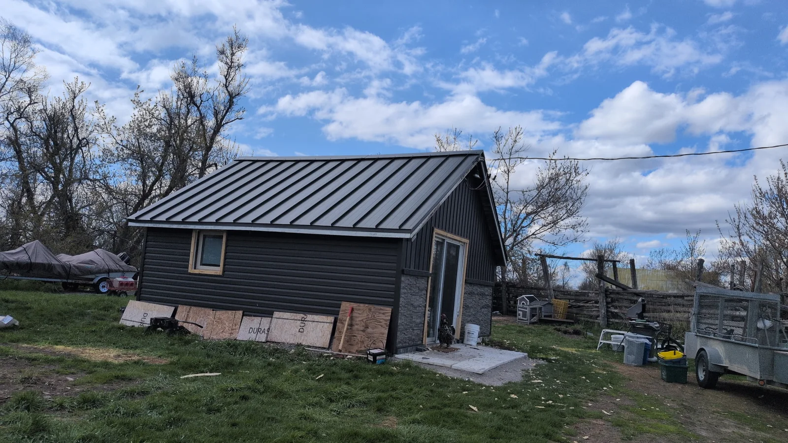 Finished wide view of a gray house with a black standing seam roof.