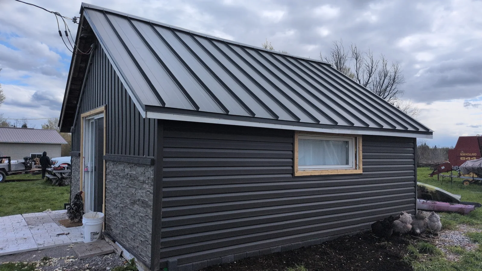 Finished side view of a gray house with a black standing seam roof.