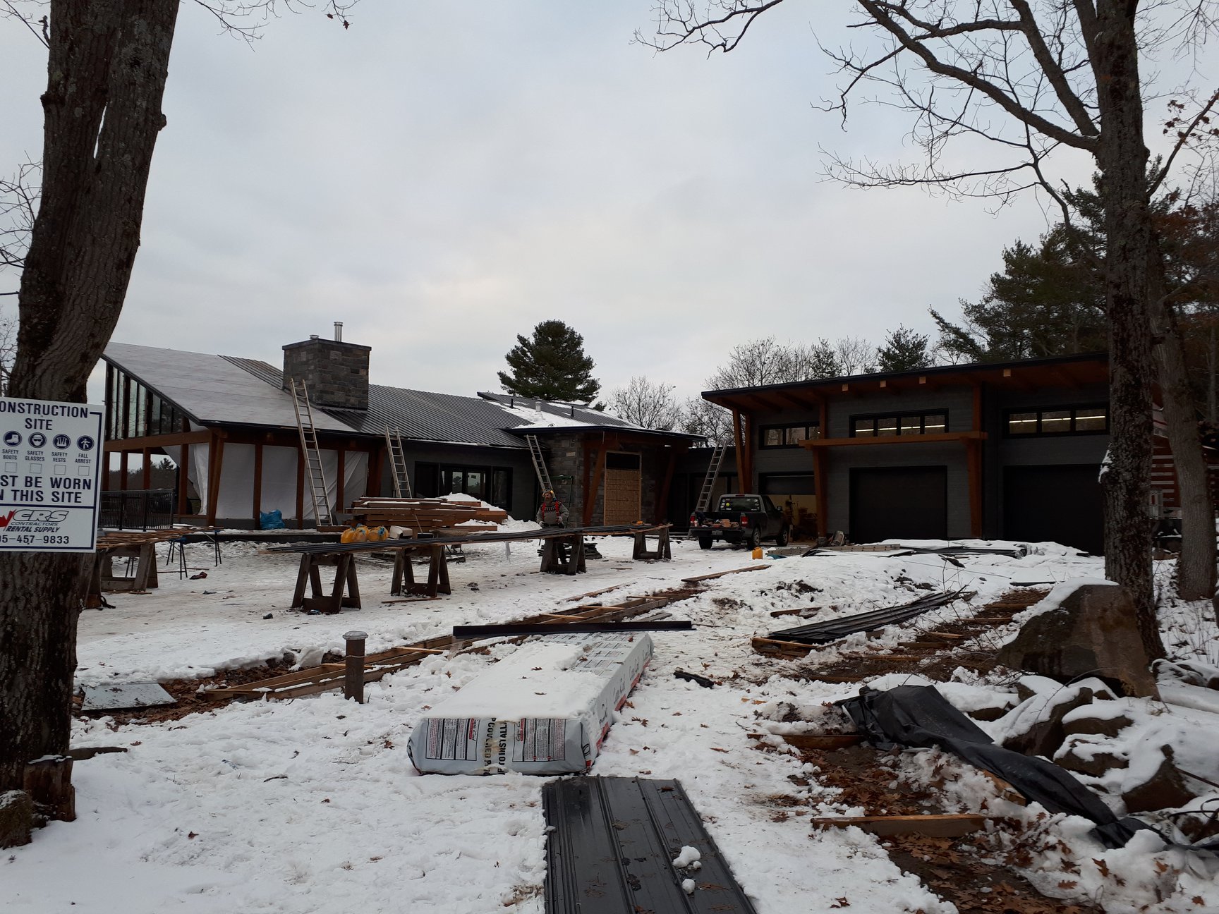 Wide winter site view of a home with dark standing seam roofing.