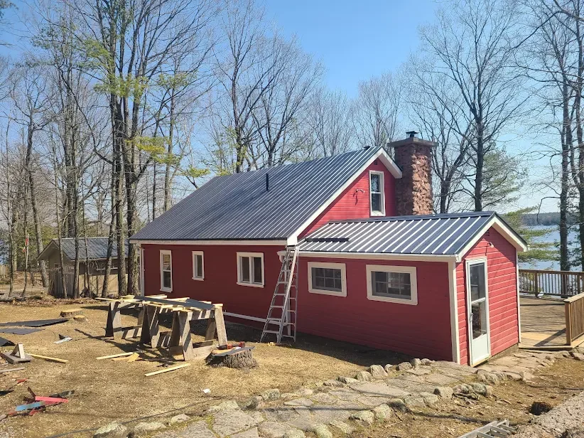 Red lakehouse with a finished grey steel roof near the water.
